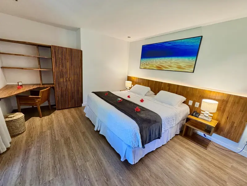 Une chambre lumineuse avec un grand lit et un bureau en bois.