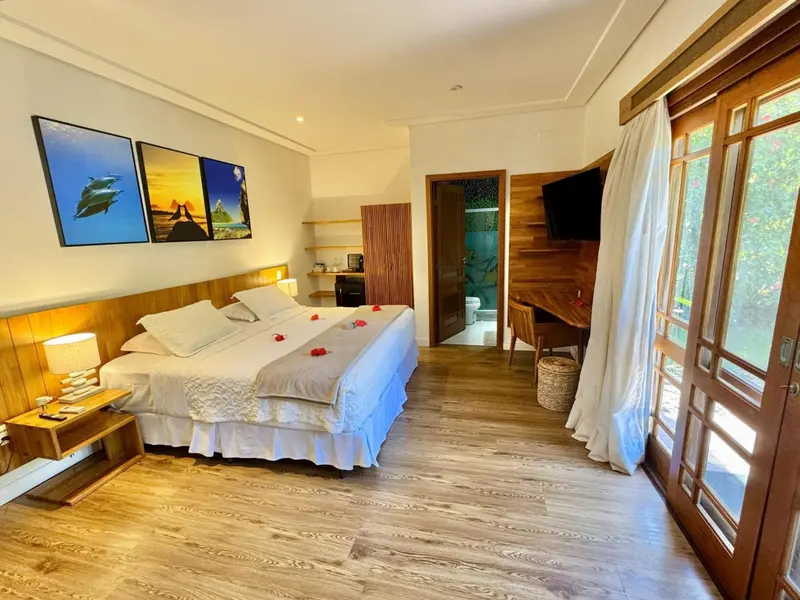 Une chambre lumineuse avec un grand lit décoré de fleurs et un bureau en bois.