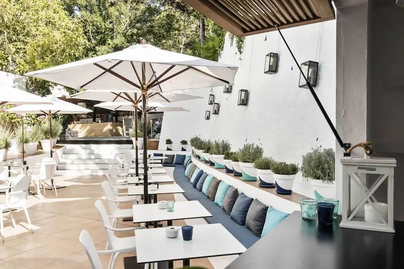 Terrasse ombragée avec tables et assises confortables.
