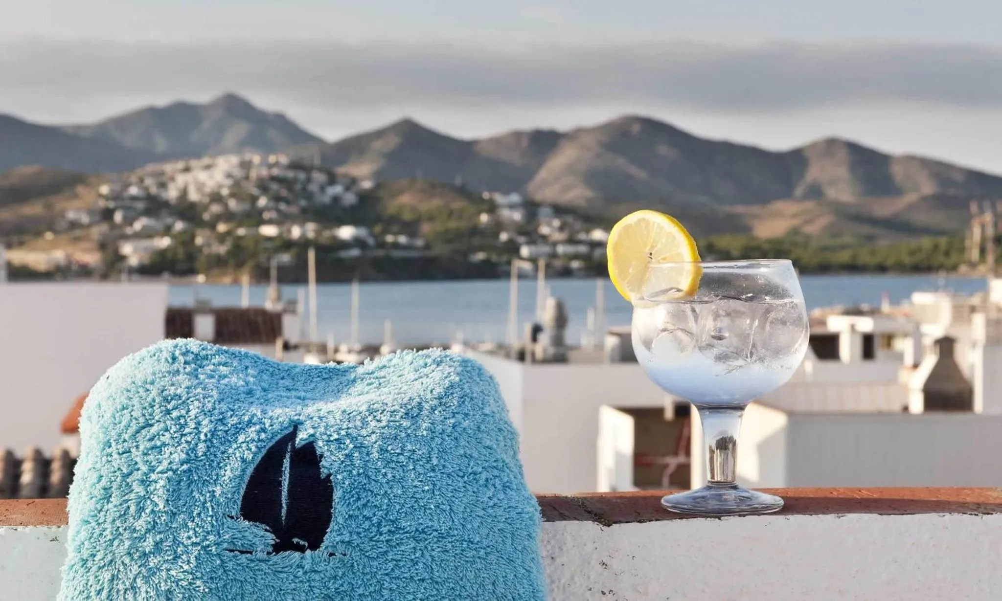 Un cocktail rafraîchissant sur une terrasse ensoleillée avec vue sur la mer et les montagnes.