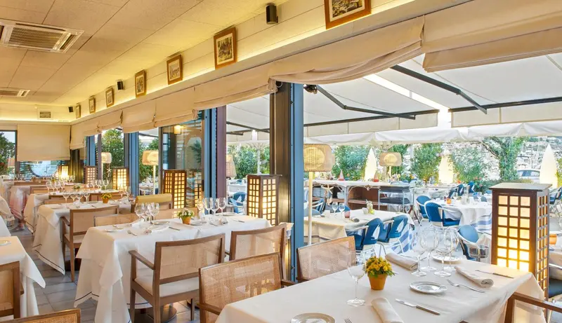 Une salle de restaurant lumineuse avec des tables dressées et une vue sur une terrasse.
