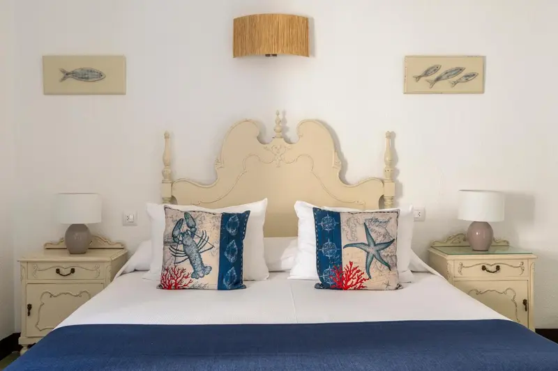 Une chambre lumineuse avec un grand lit décoré de motifs marins.