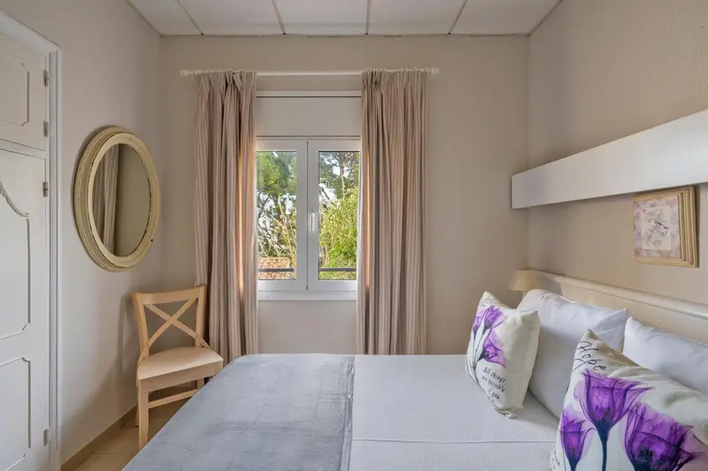 Une chambre lumineuse avec un lit double et une fenêtre.