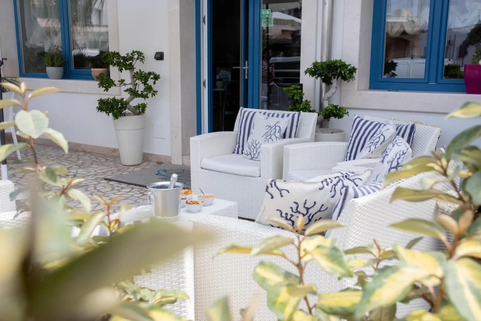 Mobilier d'extérieur blanc et coussins rayés sur une terrasse ombragée.