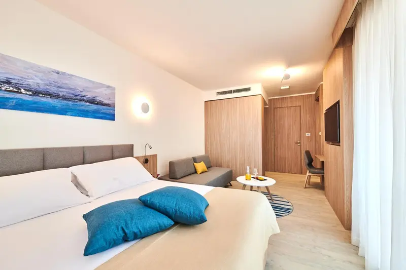 Une chambre lumineuse avec un grand lit et un coin salon.