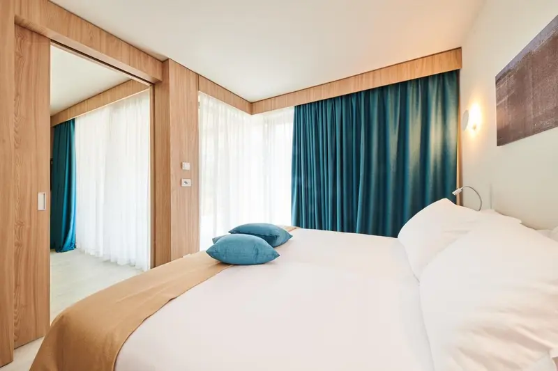 Une chambre lumineuse avec un lit fait et des coussins bleus.
