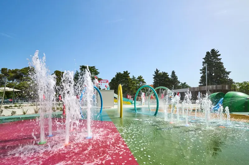 Un espace aquatique ludique avec des jets d'eau et des structures colorées.