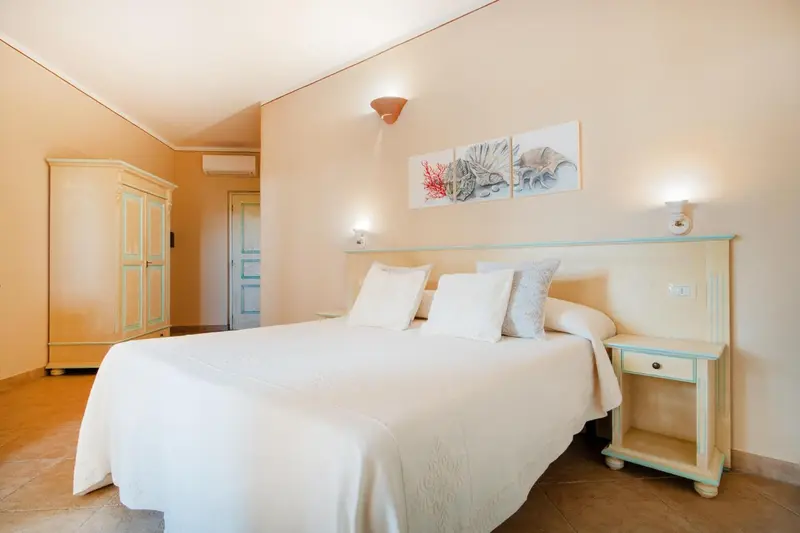 Une chambre lumineuse avec un grand lit recouvert de linge blanc.