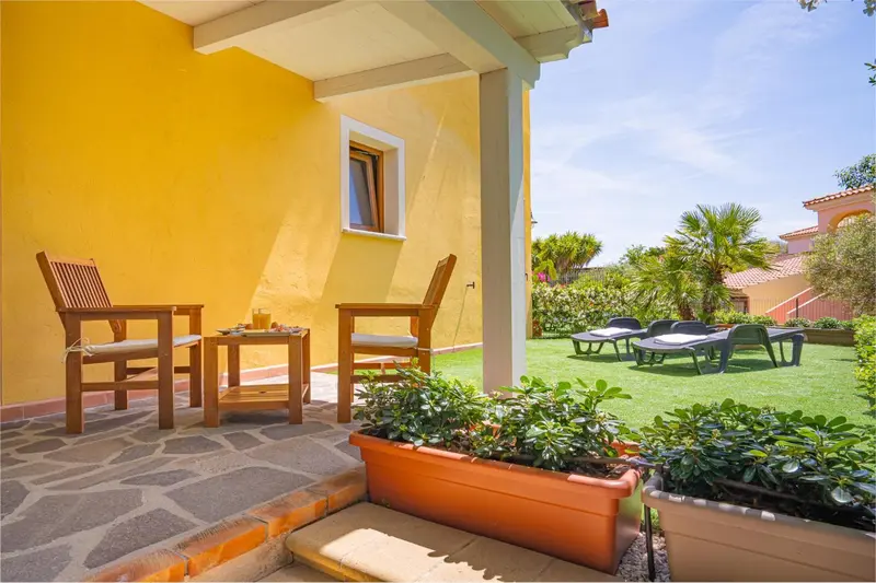 Terrasse ombragée avec mobilier en bois donnant sur un jardin soigné.