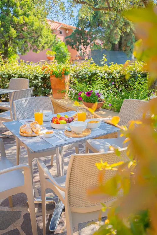Une table est dressée pour le petit-déjeuner avec des viennoiseries et des jus de fruits.