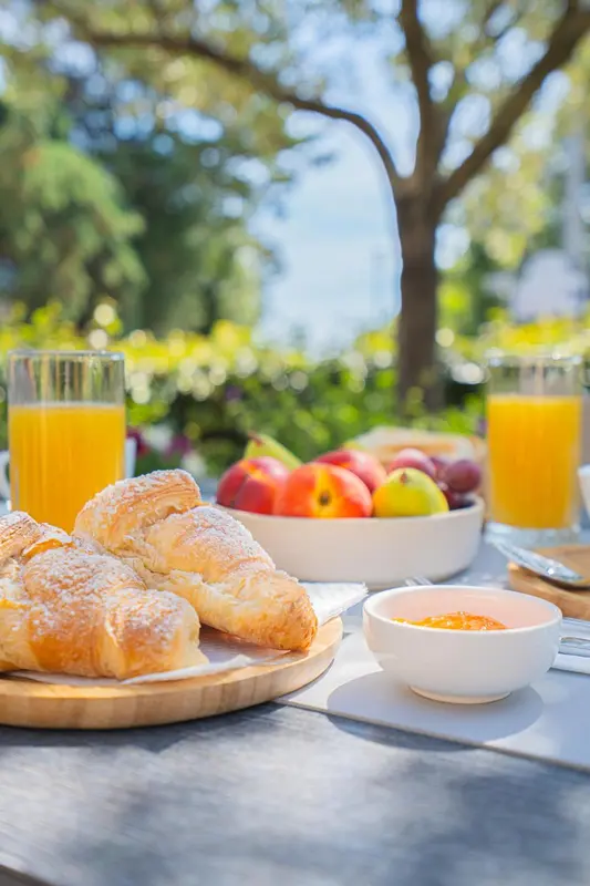 Une table est dressée avec des viennoiseries, des fruits et du jus d'orange.