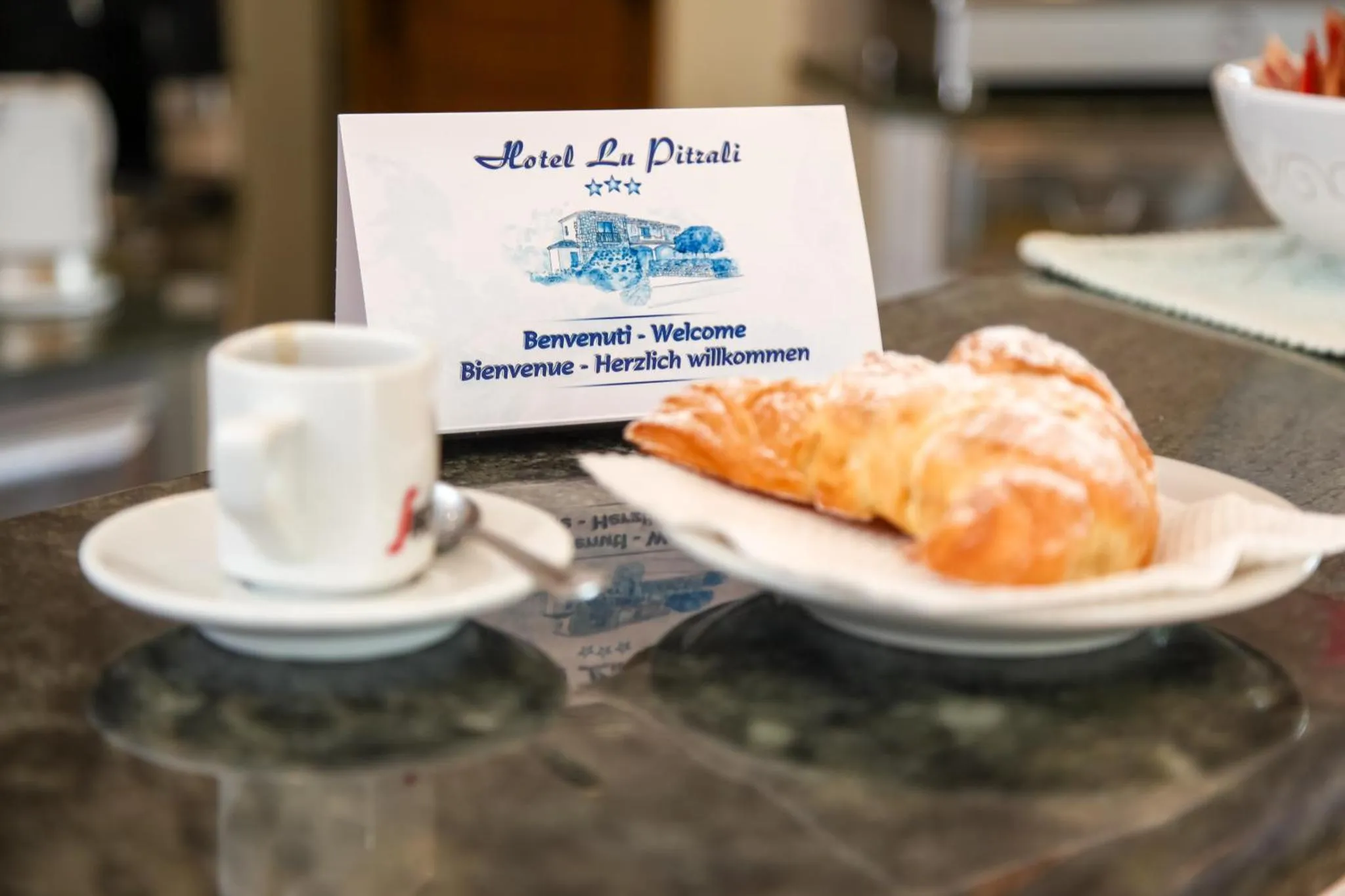 Une tasse de café, un croissant et une carte de bienvenue sont posés sur une table.