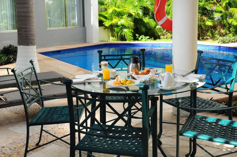 Une table est dressée pour le petit-déjeuner près d'une piscine.