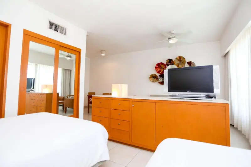 Une chambre lumineuse avec un mobilier orange et un téléviseur.