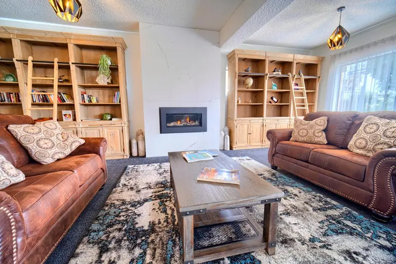 Un salon chaleureux avec deux canapés en cuir, une table basse et des bibliothèques encastrées.