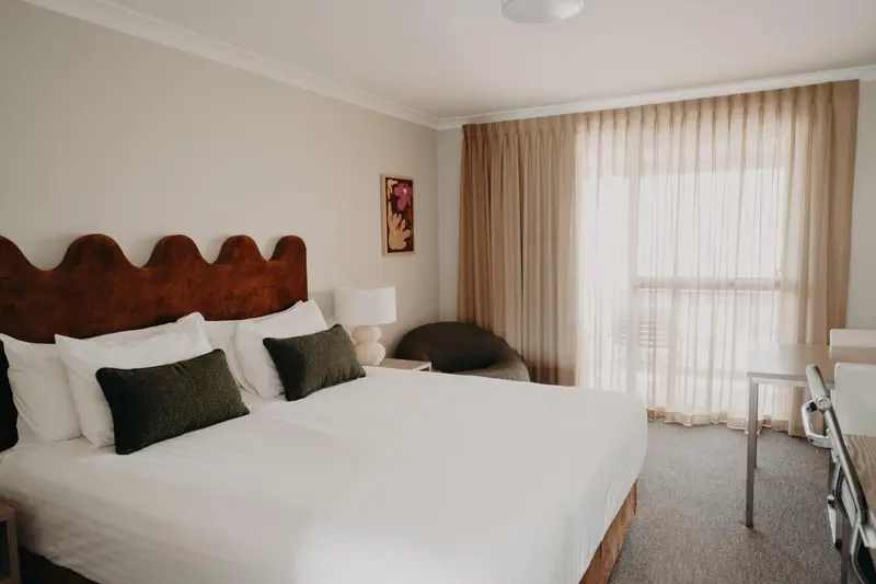 Une chambre lumineuse avec un grand lit et un bureau.
