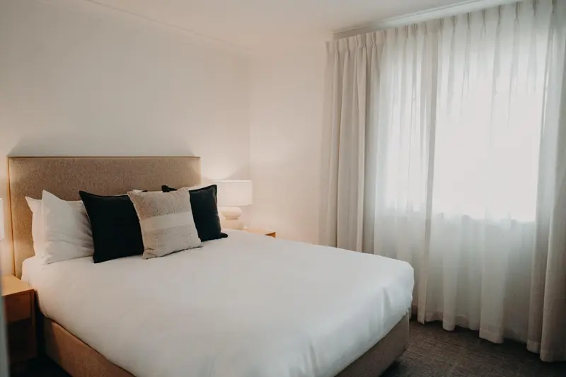 Une chambre lumineuse avec un grand lit recouvert de coussins.