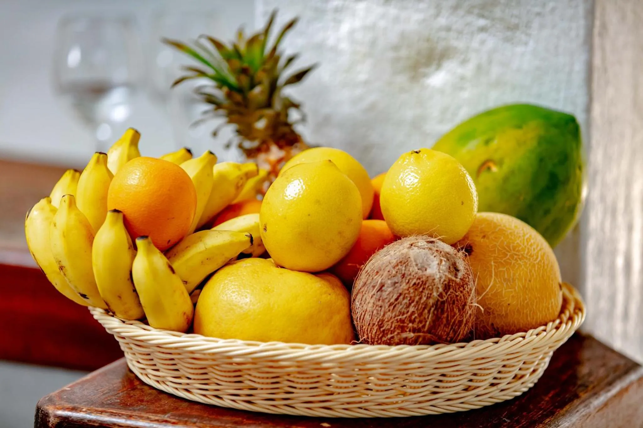 Une corbeille remplie de fruits frais tropicaux est présentée sur une table en bois.