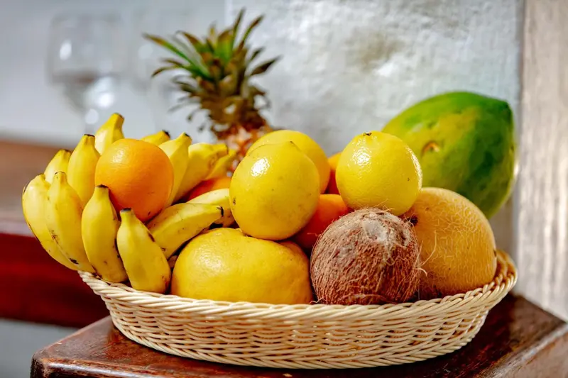 Une corbeille remplie de fruits frais tropicaux est présentée sur une table en bois.