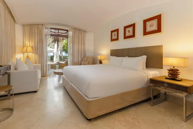 Une chambre lumineuse avec un grand lit et un coin salon.