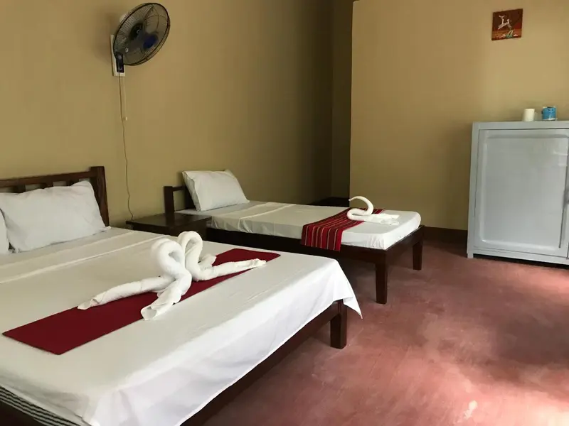 Une chambre avec deux lits simples décorés de serviettes en forme de cygnes.
