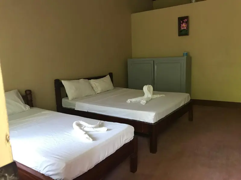 Une chambre avec deux lits simples et une commode.
