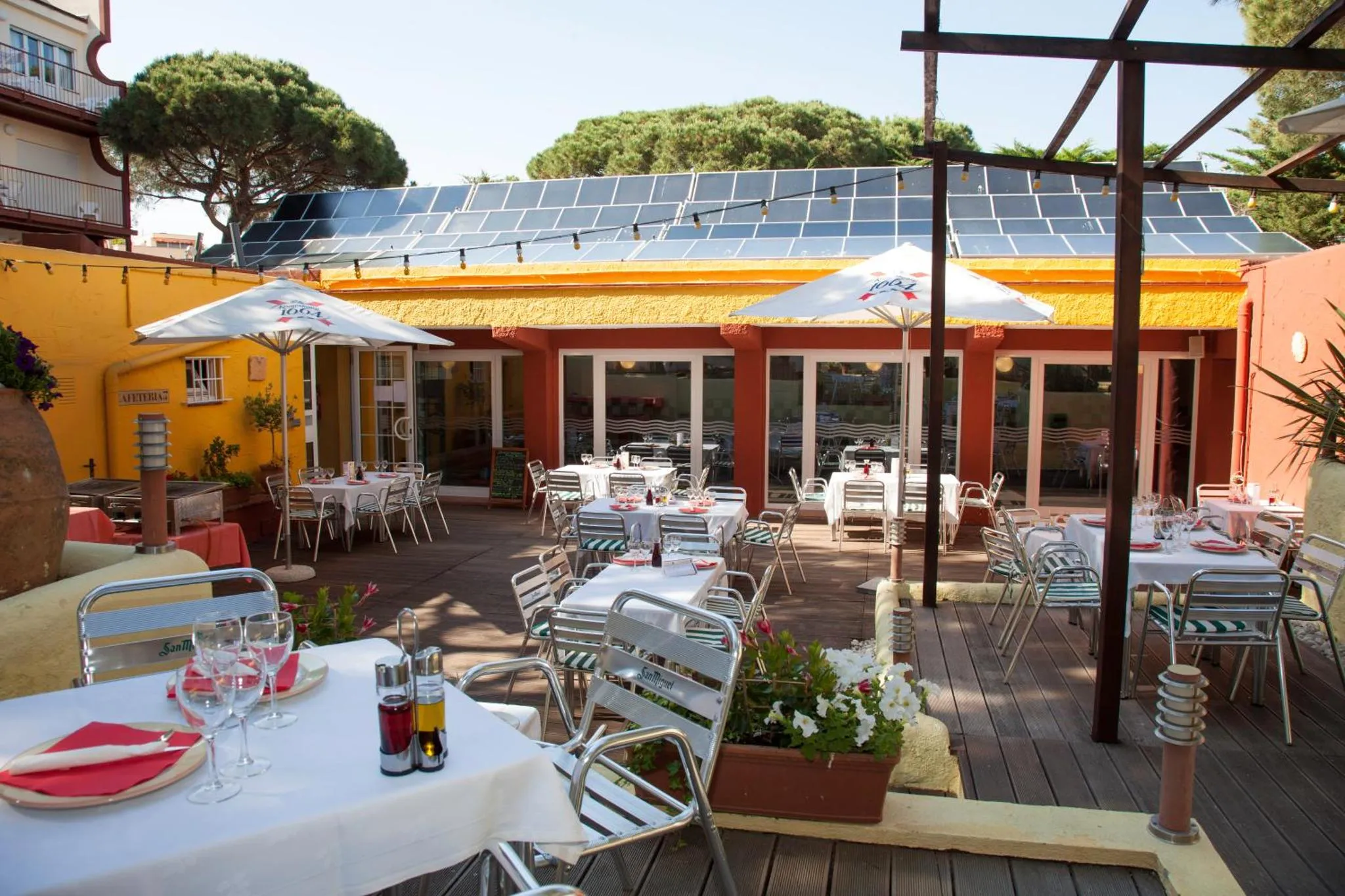Terrasse ombragée avec tables nappées et chaises métalliques.