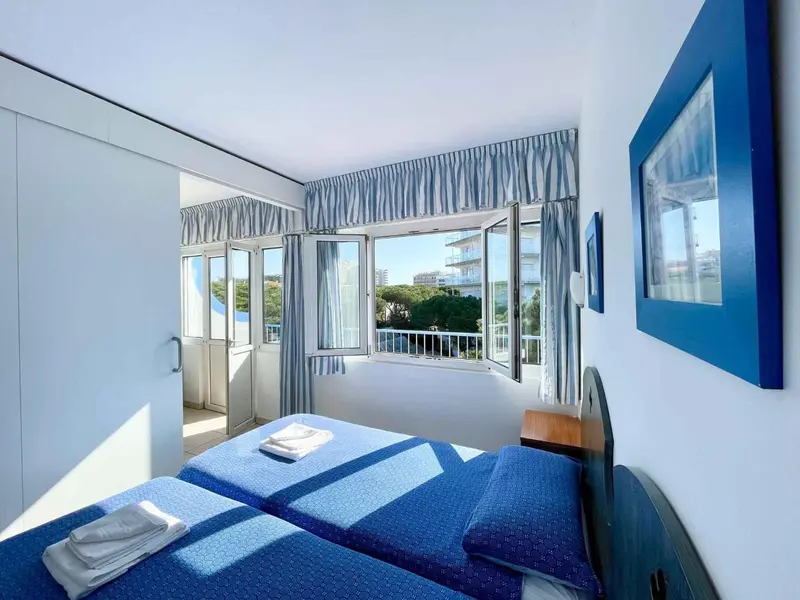 Chambre lumineuse avec vue sur la mer depuis un balcon.
