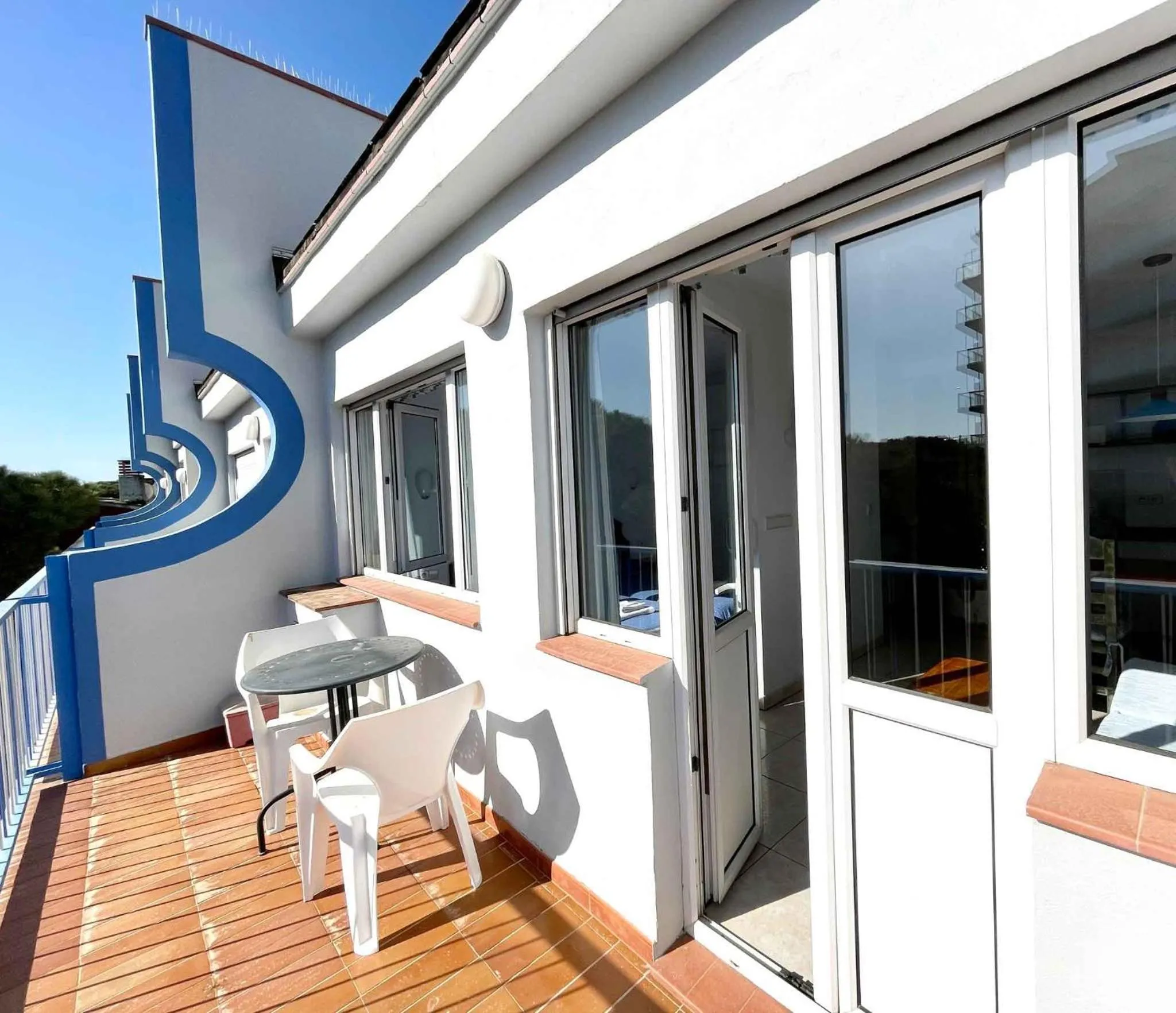 Terrasse avec mobilier blanc et vue sur la mer.