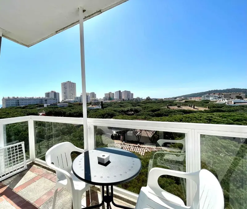 Terrasse avec mobilier d'extérieur et vue sur la ville et la végétation.