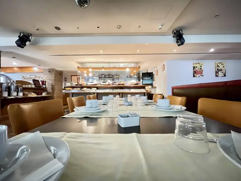 Une salle de restaurant lumineuse avec des tables dressées et un comptoir de buffet.