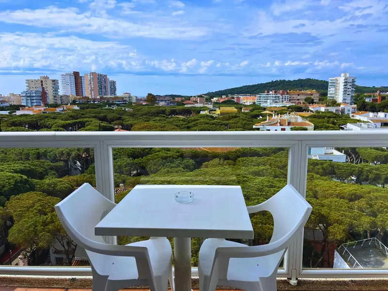 Vue d'une terrasse avec une table et des chaises donnant sur une ville côtière et une végétation luxuriante.
