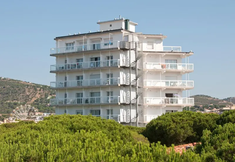 Bâtiment blanc à plusieurs étages avec des balcons et des escaliers extérieurs.