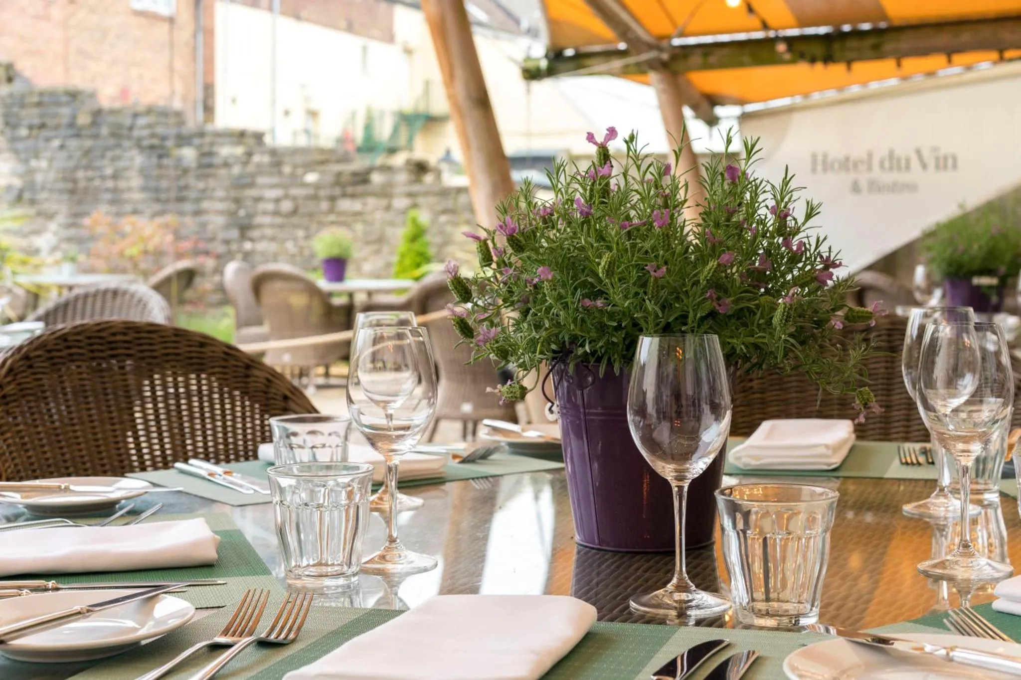 Une table dressée avec de la vaisselle et des couverts sur une terrasse fleurie.