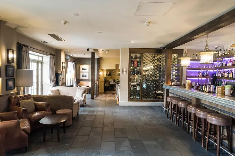 Un espace de détente avec des canapés et fauteuils face à un long comptoir de bar.