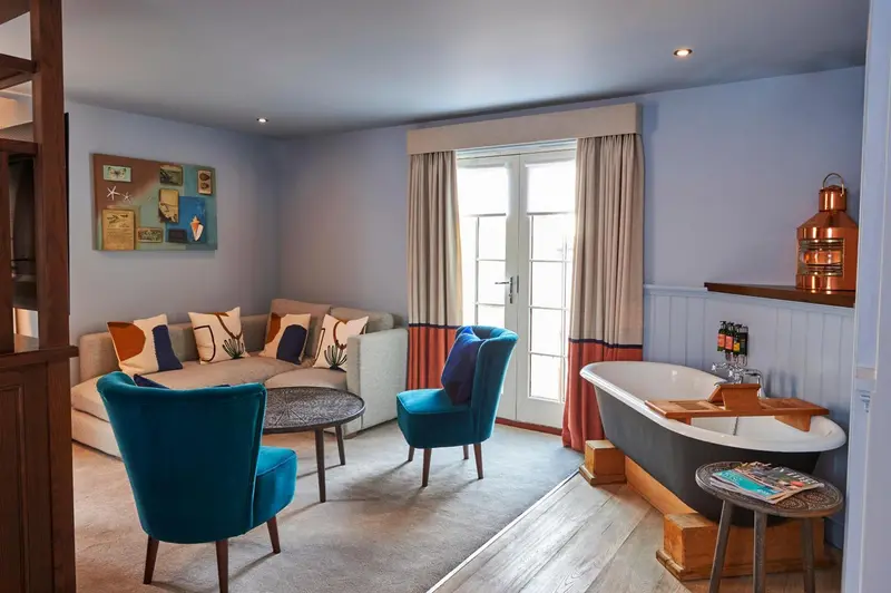 Un salon confortable avec canapés et fauteuils ouvre sur une salle de bain avec baignoire.