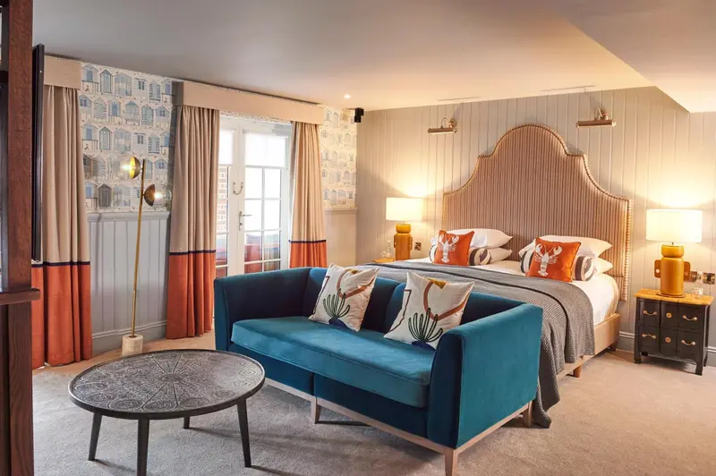 Une chambre lumineuse avec un grand lit et un canapé bleu turquoise.