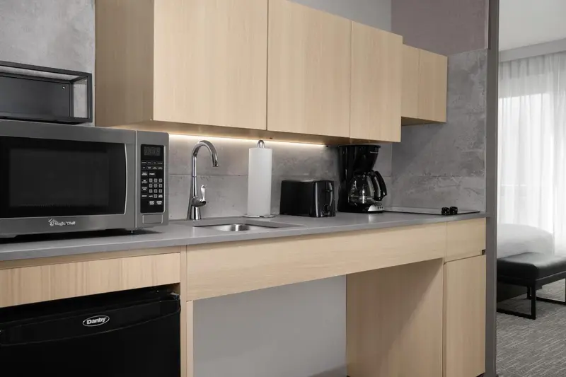 Une kitchenette moderne avec un micro-ondes, un évier et une cafetière.