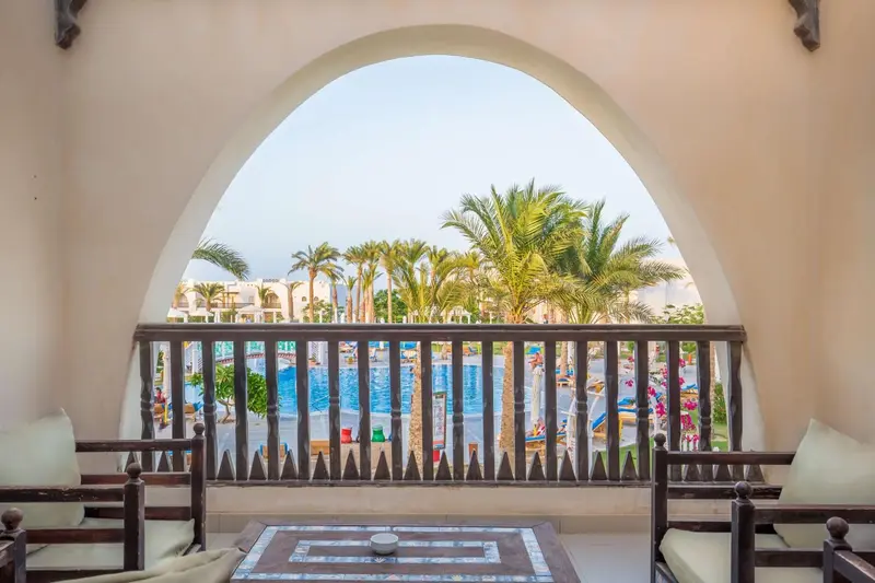 Vue sur une piscine et une végétation luxuriante depuis un balcon.