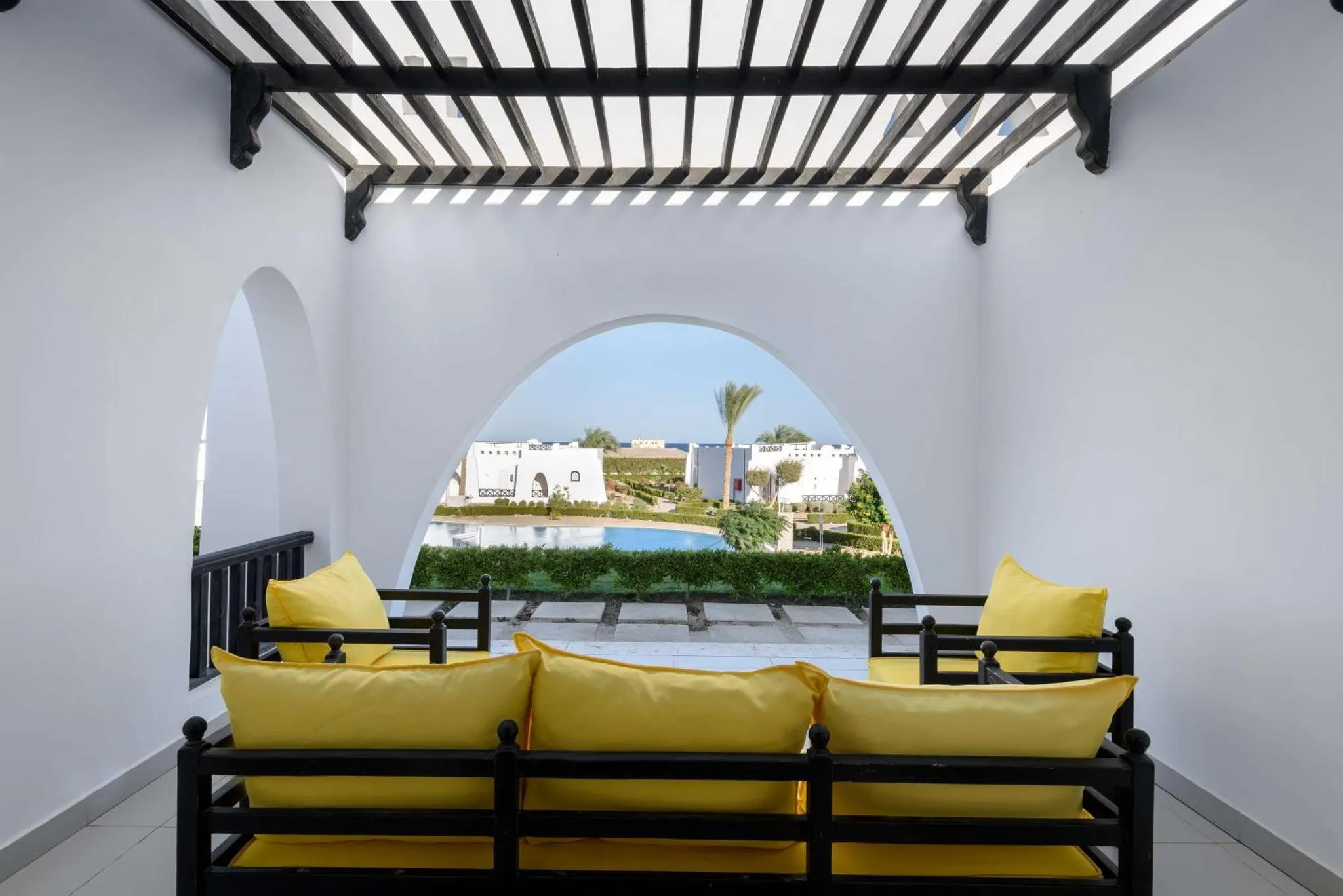 Vue sur une piscine depuis un espace de détente ombragé.