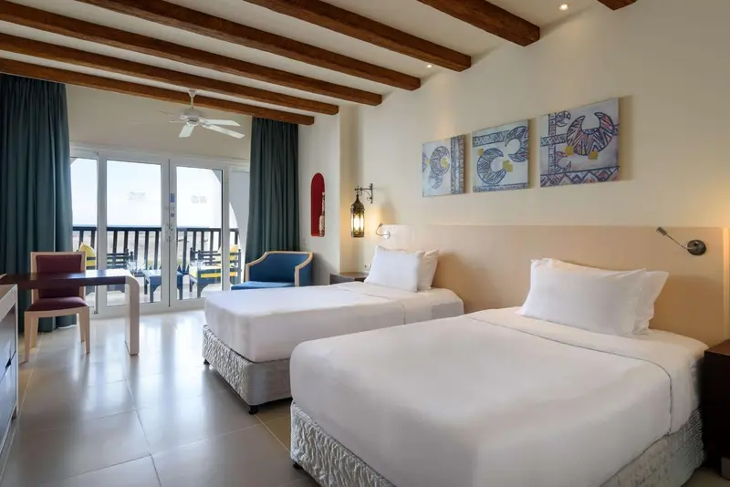 Une chambre lumineuse avec deux lits simples et vue sur la mer.