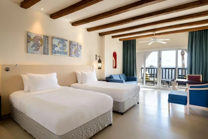 Une chambre lumineuse avec deux lits et un espace détente.