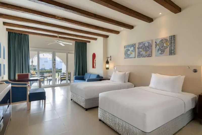 Une chambre lumineuse avec deux lits simples et un coin salon.