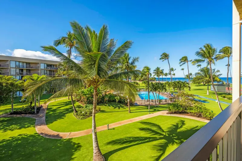 Vue sur une végétation luxuriante et une piscine depuis un balcon.