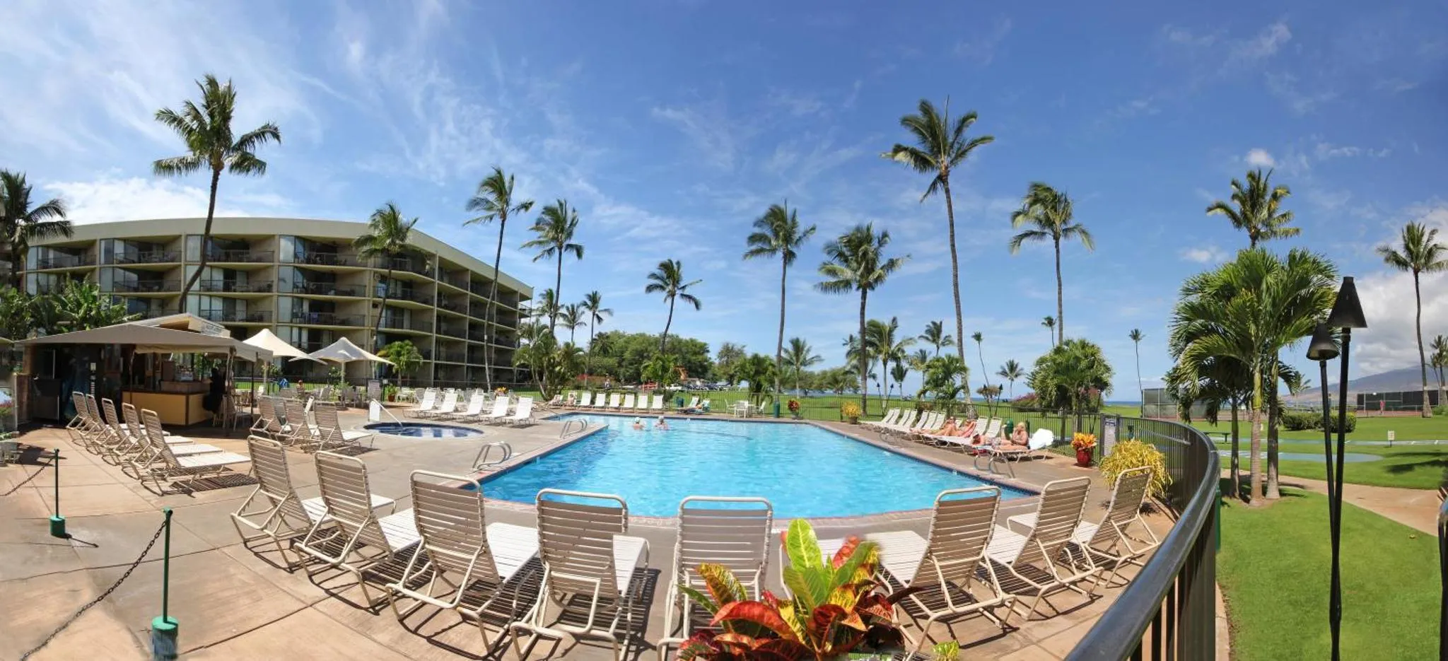 Vue d'une piscine bordée de transats dans un complexe hôtelier tropical.