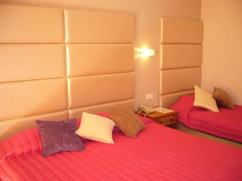 Une chambre avec deux lits et une tête de lit rembourrée.
