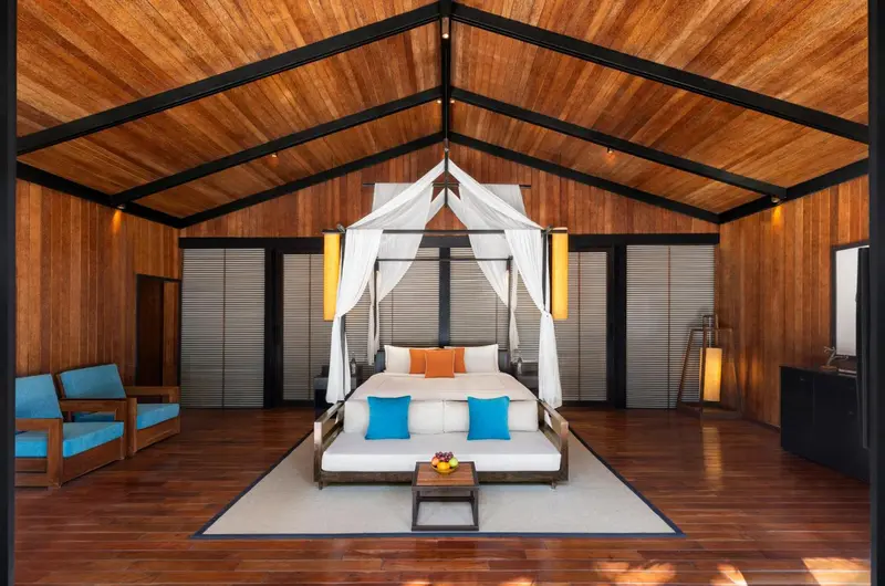 Une chambre lumineuse avec un lit à baldaquin et une décoration tropicale.