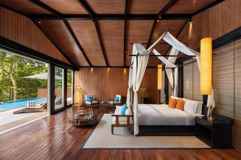 Une chambre spacieuse avec un lit à baldaquin et une vue sur une piscine.