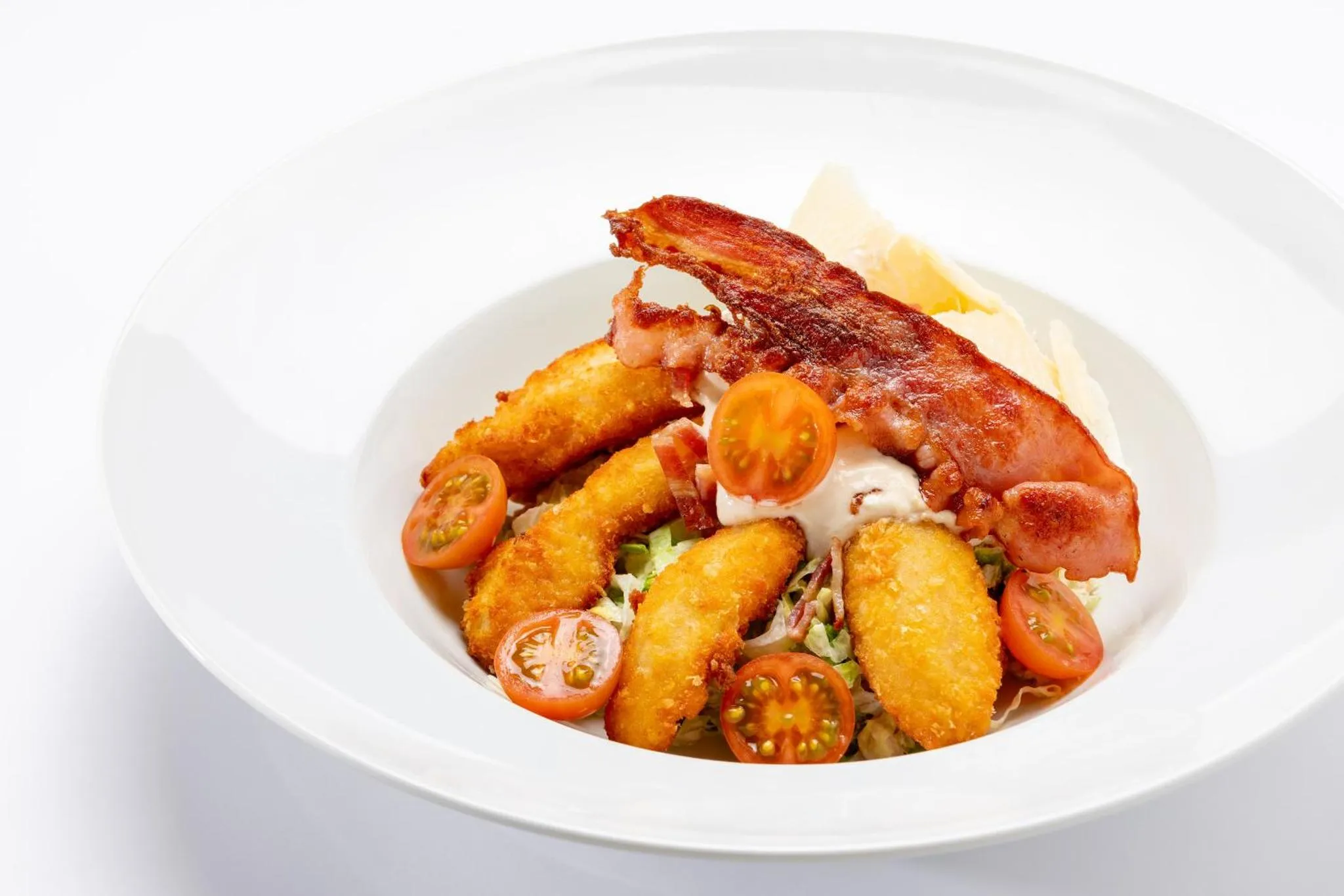 Assiette de frites panées garnies de lardons et de tomates cerises.
