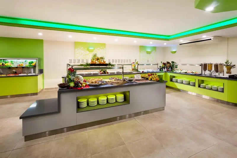 Un buffet de fruits et de pâtisseries est présenté dans une salle lumineuse.